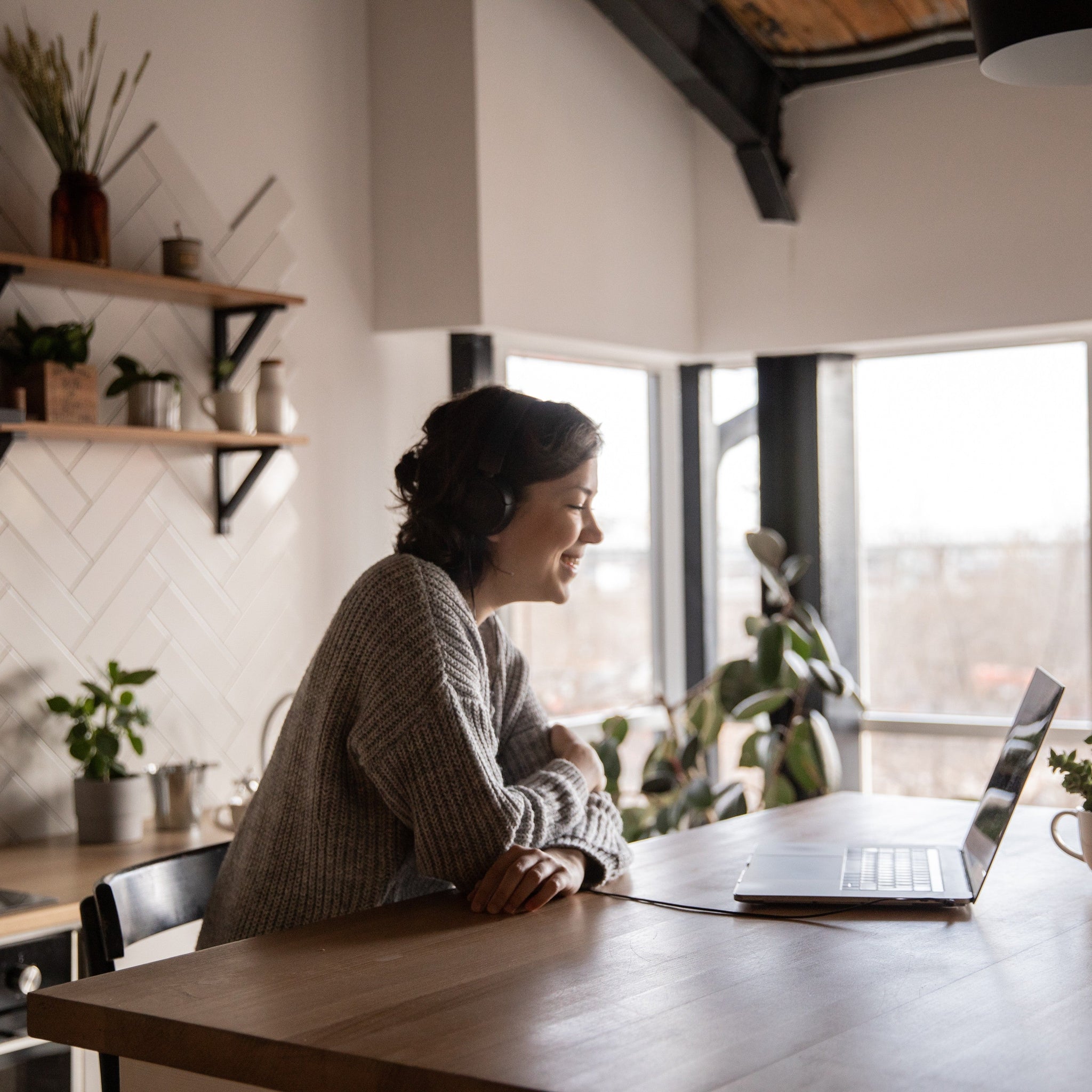 Happy woman video chatting on a laptop in kitchen