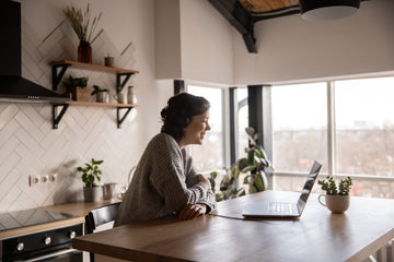 Happy woman video chatting on a laptop in kitchen