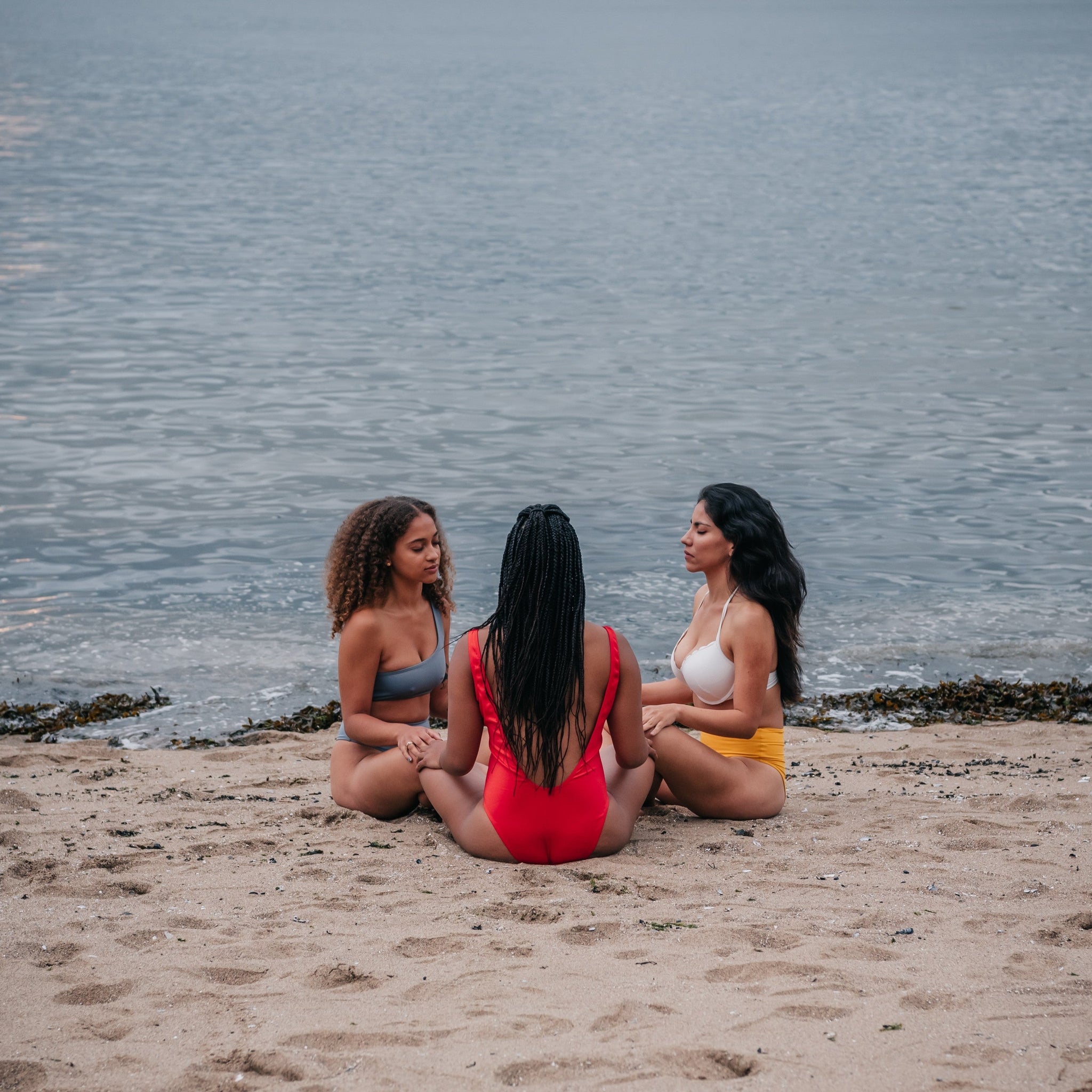 Three women meditating on a beach