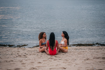 Three women meditating on a beach