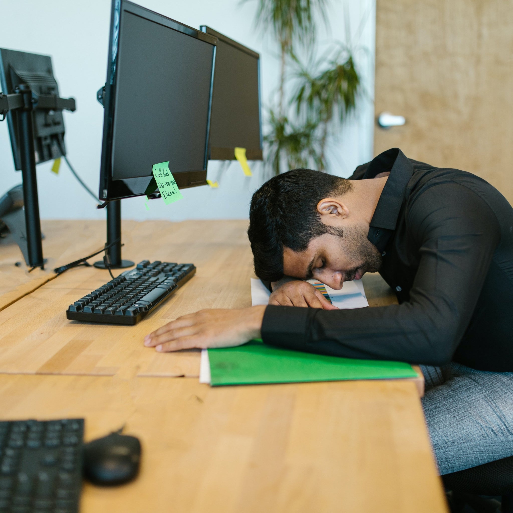 An Indian man laying his head on his work desk