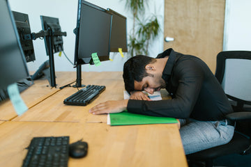 An Indian man laying his head on his work desk