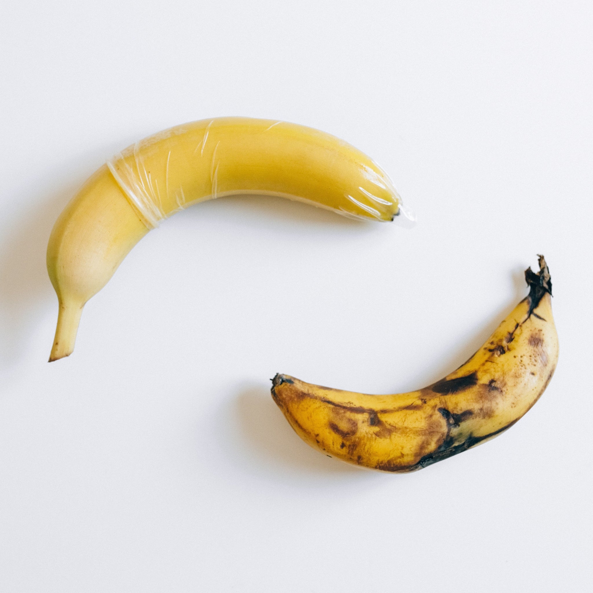 Condom on a yellow banana and a brown banana