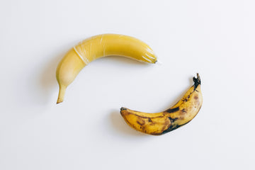 Condom on a yellow banana and a brown banana