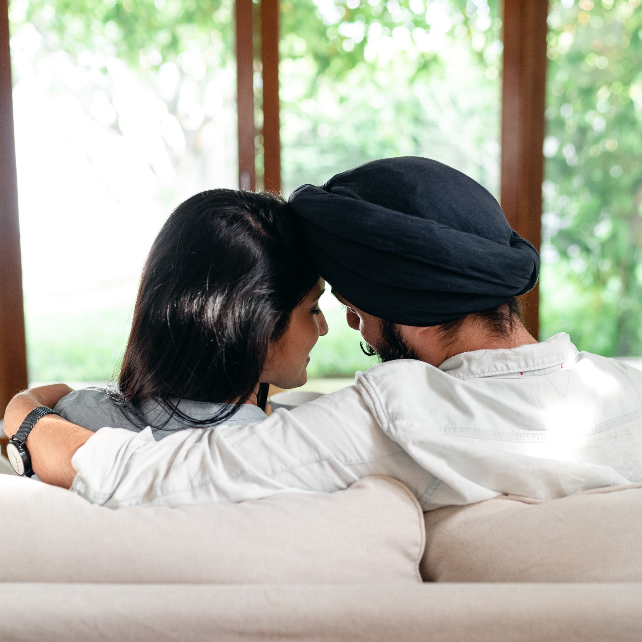 Cuddling young Indian couple resting on sofa