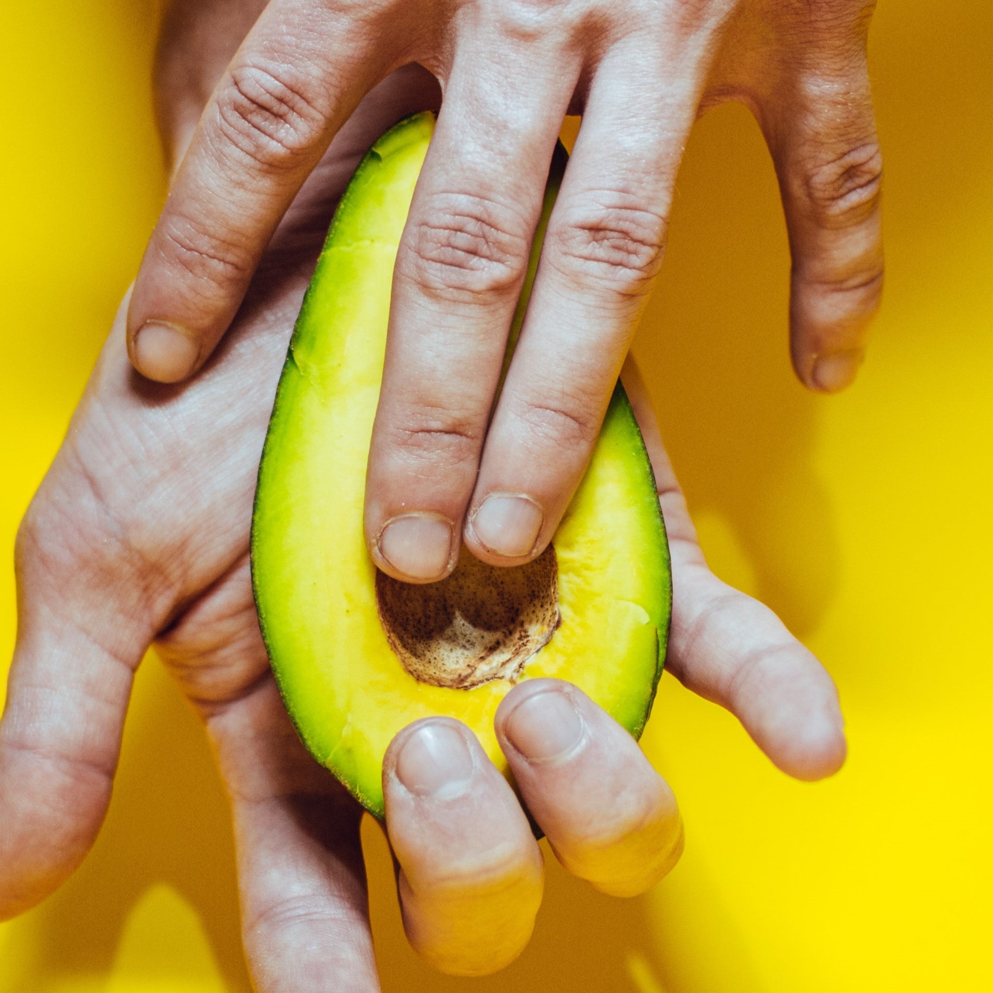 A hand rubbing an avocado