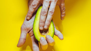 A hand rubbing an avocado