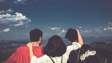 A Woman Standing Between Two Men Facing Mountains