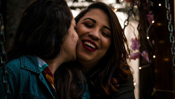 A Smiling Women Kissing Another Woman