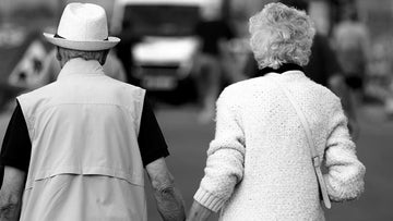 An old couple holding hands, facing away from the camera